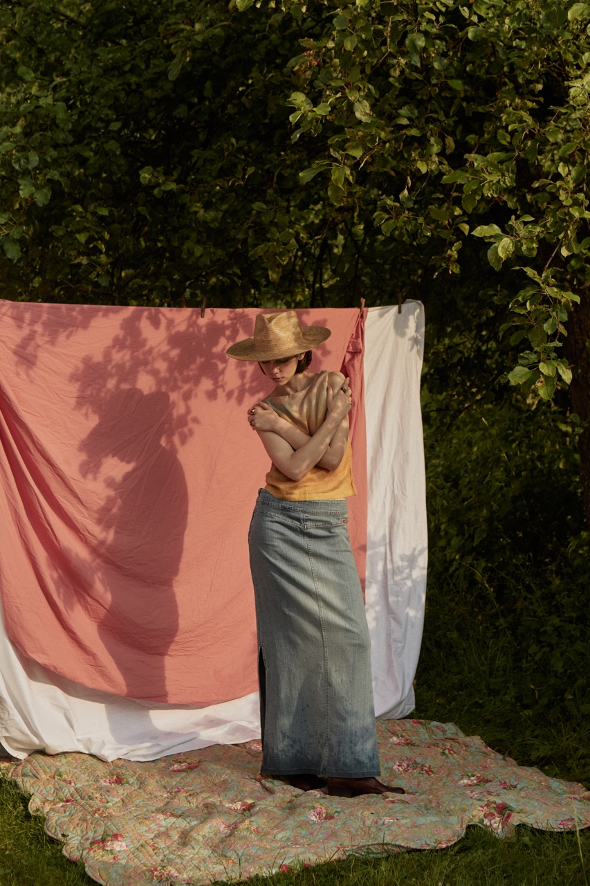 Artistic portrait of a woman wearing the PIAVE handmade straw fedora hat casting a shadow against a pink fabric backdrop.