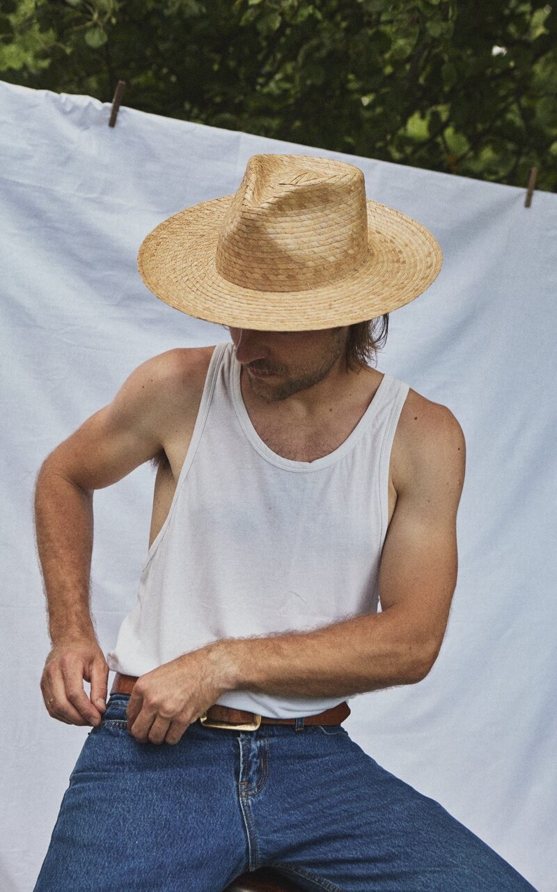 Man wearing the PIAVE II handmade straw fedora hat with a wide brim and natural woven texture.