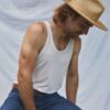 Man seated outdoors wearing the PIAVE II handwoven straw fedora hat in a relaxed summer setting.