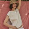 Woman wearing the TICINO handwoven sea grass hat with a soft bucket silhouette and linen top.