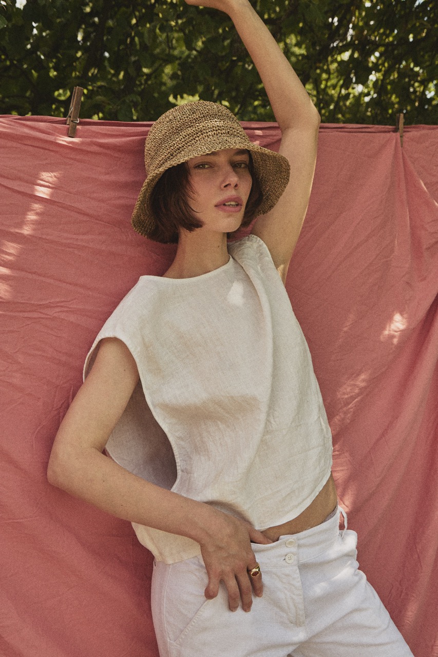 Woman wearing the TICINO handwoven sea grass hat with a soft bucket silhouette and linen top.
