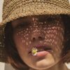 Close-up portrait of a woman wearing the TICINO handmade sea grass summer hat.
