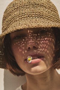 Close-up portrait of a woman wearing the TICINO handmade sea grass summer hat.