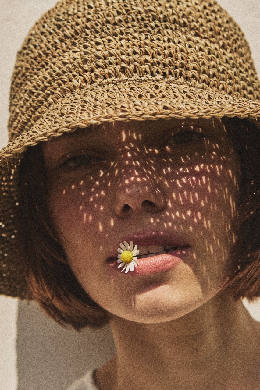 Close-up portrait of a woman wearing the TICINO handmade sea grass summer hat.