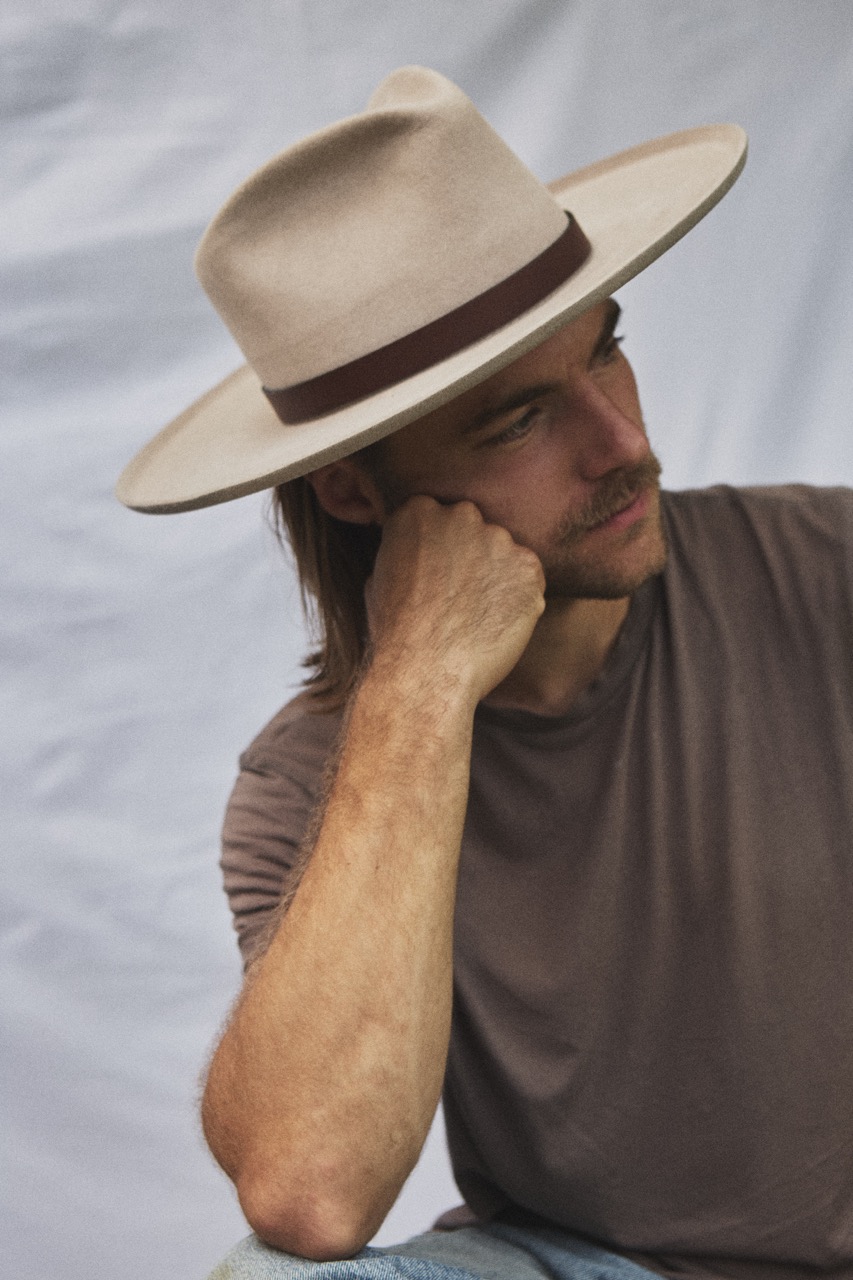 Close-up side portrait of a man wearing the PIAVE natural straw fedora hat outdoors.
